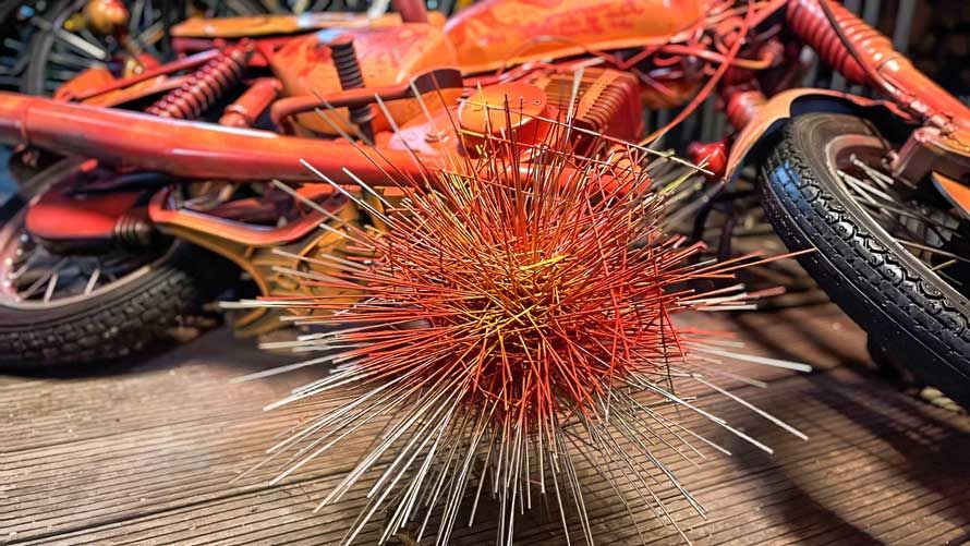 Metallstachel vor orangem Motorrad - Kunst von Wolfgang Kaliga
